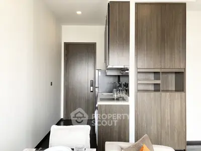 Modern compact kitchen with sleek wooden cabinetry and integrated appliances, adjacent to a cozy living area, perfect for urban living.