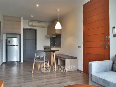 Modern open-plan living room with kitchen and dining area, featuring sleek furniture and wooden flooring.