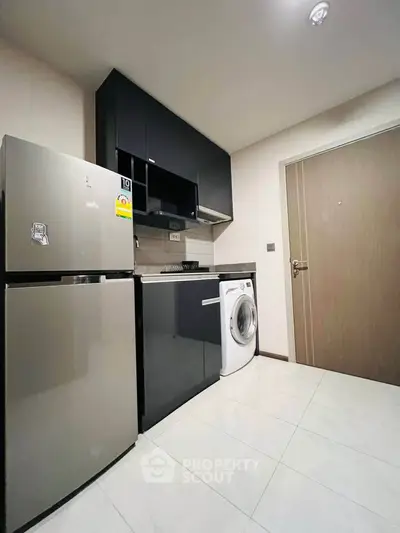 Modern kitchen with sleek appliances and washing machine in compact layout