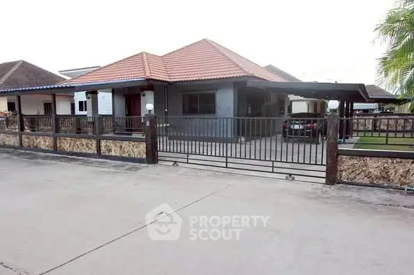 Charming single-story house with tiled roof and gated driveway in suburban neighborhood.