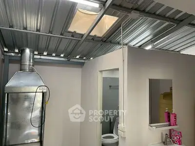 Compact kitchen area with metal roof and adjacent bathroom, featuring basic amenities.