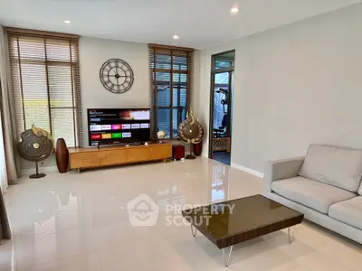 Modern living room with sleek furniture and large windows, featuring a stylish entertainment center and elegant decor.