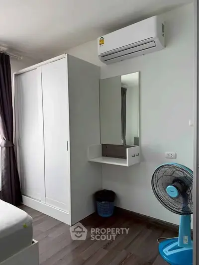 Modern bedroom with air conditioning, wardrobe, and fan in a cozy apartment.