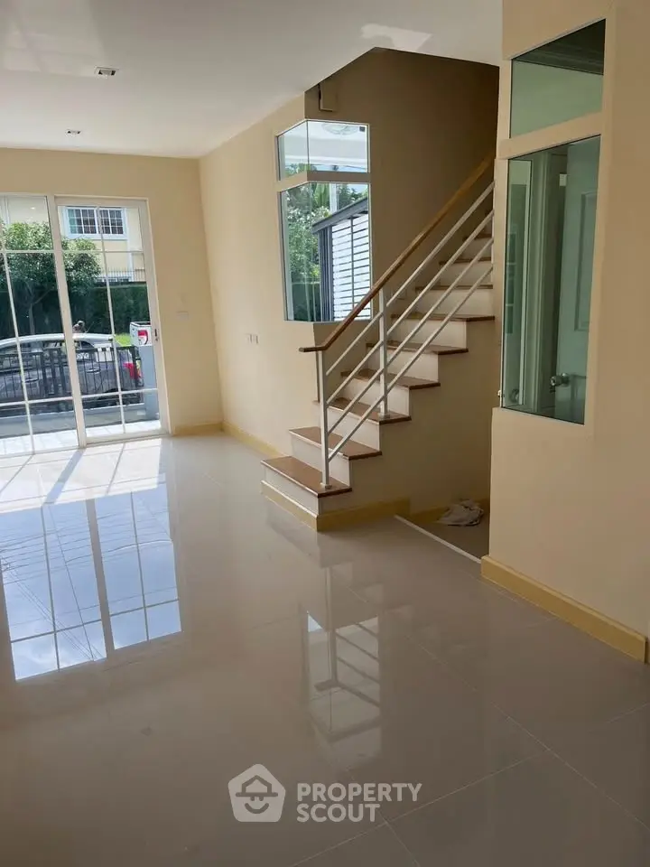 Bright and airy living room with staircase and large windows