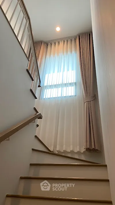 Elegant staircase with natural light and modern curtains in a stylish home
