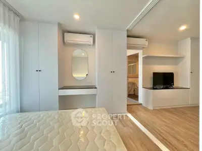 Modern bedroom with built-in wardrobe and air conditioning, featuring a sleek vanity and TV setup.