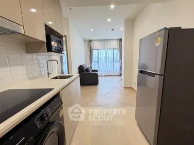 Modern open-layout kitchen with appliances leading to a cozy living room with city view.