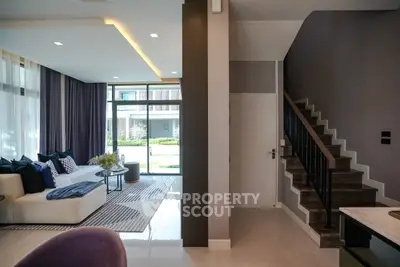 Modern living room with stylish decor and staircase in a bright, open space.