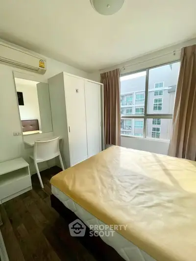 Bright bedroom with large window and modern furnishings in a stylish apartment.