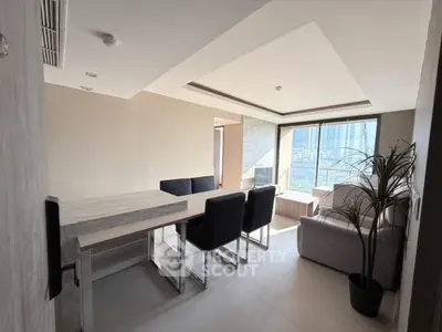 Modern living room with dining area and city view, featuring sleek furniture and large windows.