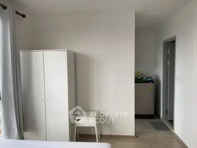 Minimalist bedroom with white wardrobe and washing machine in modern apartment.