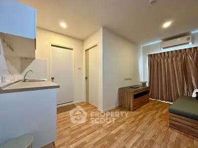 Modern apartment interior with wooden flooring and compact kitchen area.