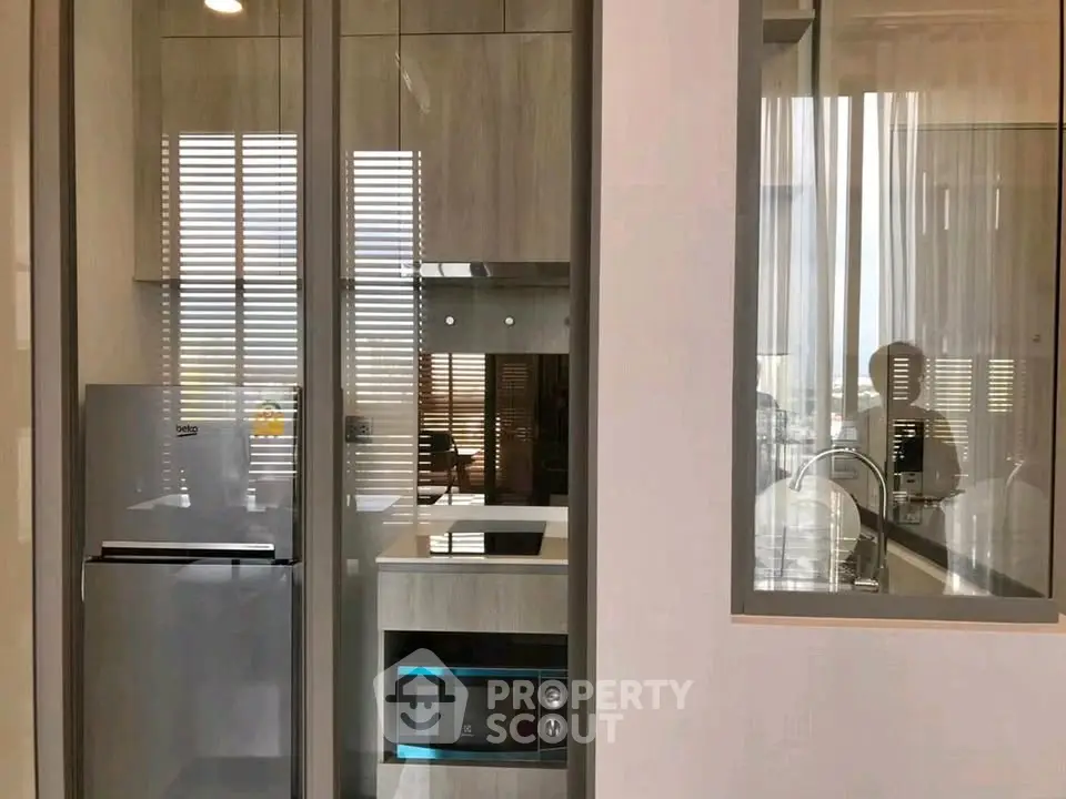 Modern kitchen with sleek appliances and glass partition in stylish apartment.