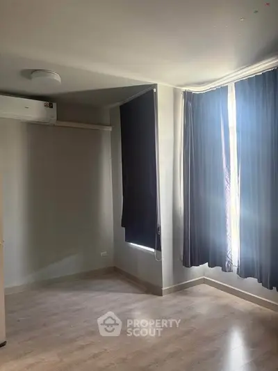 Spacious empty room with large window and air conditioning, perfect for customization.