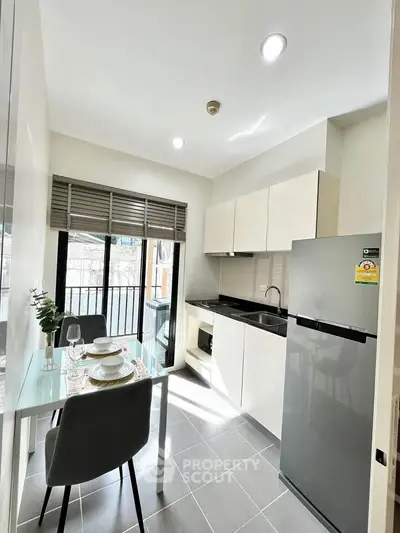 Modern kitchen with sleek cabinets and dining area in bright apartment