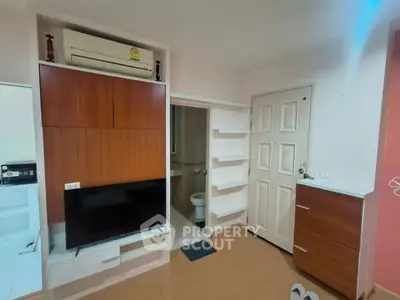 Compact living space with wall-mounted TV and air conditioning, featuring a small bathroom entrance.