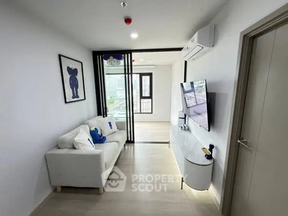 Modern living room with sleek design and city view, featuring a cozy white sofa and wall-mounted TV.