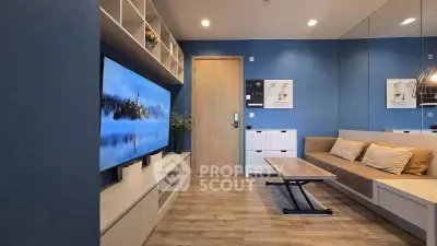 Modern living room with blue walls, large TV, and cozy seating area.