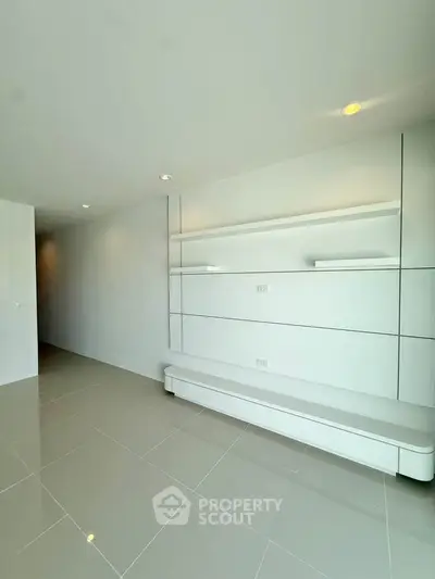 Spacious modern living room with sleek built-in shelving and glossy tiled flooring.