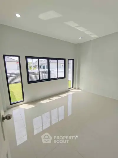 Bright empty room with large windows and glossy floor, perfect for customization.