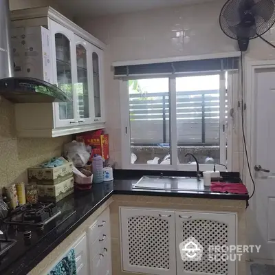 Compact kitchen space with gas stove, ample cabinetry, and natural light streaming through a large window, ideal for culinary enthusiasts.