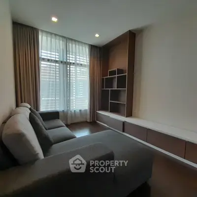 Spacious living room with modern sofa and large window, perfect for relaxation.