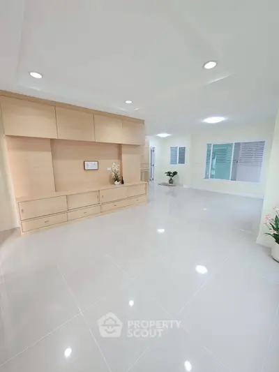 Spacious modern living room with sleek tile flooring and built-in wooden storage unit.