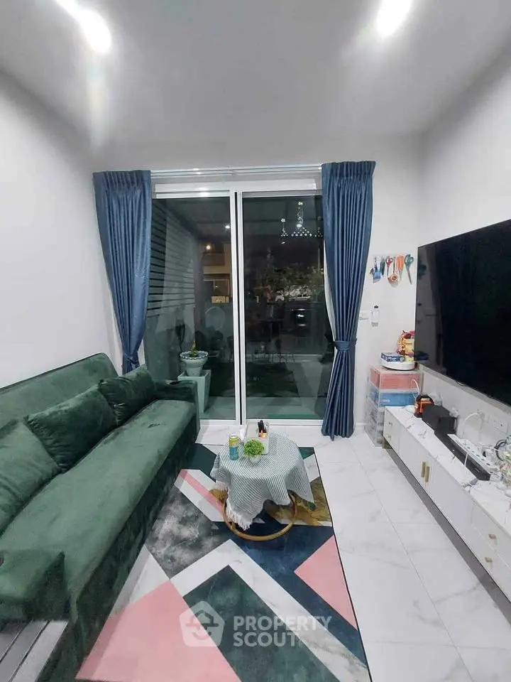 Modern living room with green sofa, large TV, and stylish decor in a cozy apartment.