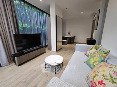 Modern living room with stylish decor and large TV, featuring floor-to-ceiling windows and elegant furnishings.