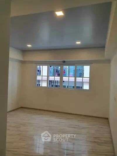 Spacious empty room with large windows and modern lighting, perfect for customization.