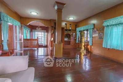 Spacious living room with wooden floors and large windows in a cozy home.