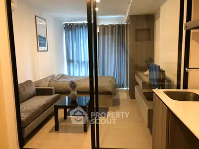 Modern studio apartment with cozy living area and bed, featuring sleek design and natural light.