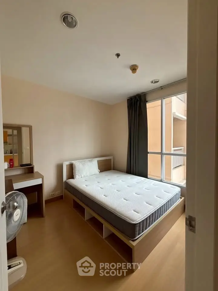 Cozy bedroom with large window and modern furnishings, perfect for relaxation.