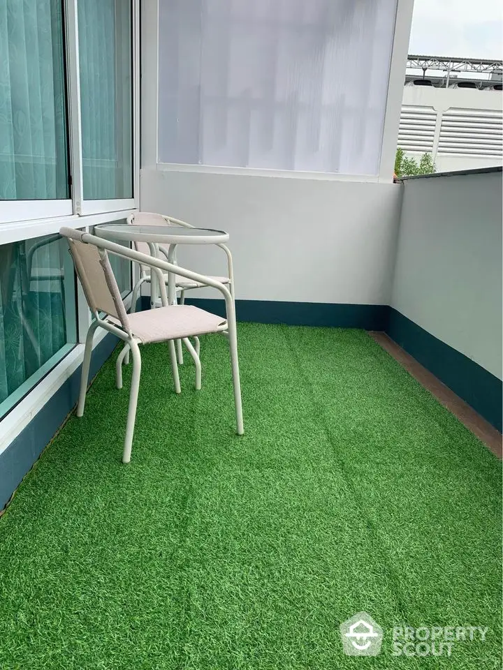 Charming balcony with artificial grass and cozy seating area, perfect for relaxation.