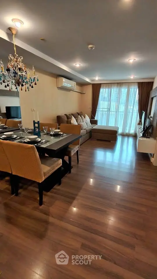 Spacious living room with elegant chandelier and modern furnishings in a cozy apartment.