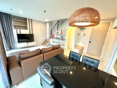 Modern living room with stylish decor and open layout, featuring a cozy brown sofa and sleek black dining table.