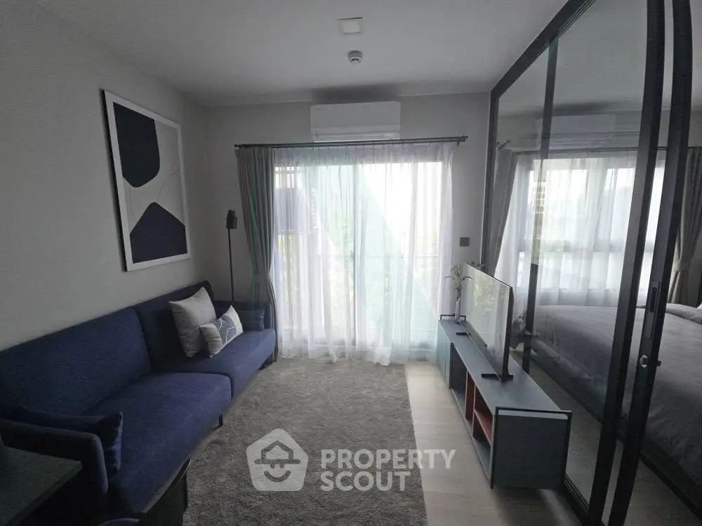 Modern living room with blue sofa, large window, and sleek TV setup