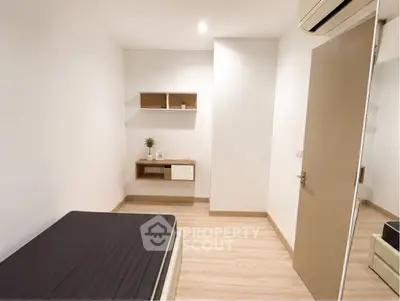 Minimalist bedroom with wooden flooring and wall-mounted shelves in modern apartment.