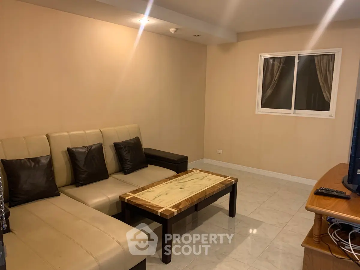 Cozy living room with beige sofa and marble coffee table, ideal for relaxation.