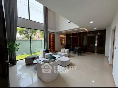 Spacious modern living room with high ceilings and elegant decor, featuring large windows and stylish furniture.