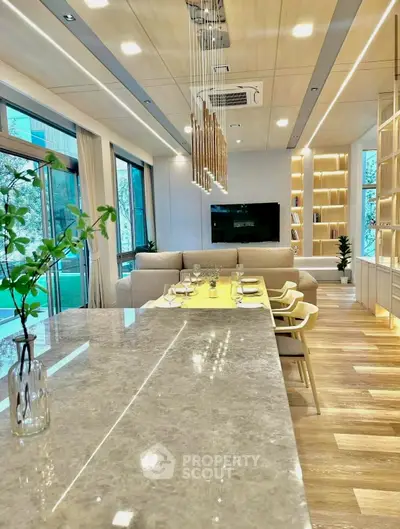 Luxurious modern living room with open layout and elegant dining area, featuring stylish lighting and large windows.