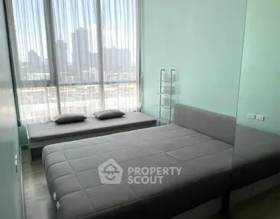 Modern bedroom with large window and city view, featuring a stylish bed and cozy seating area.