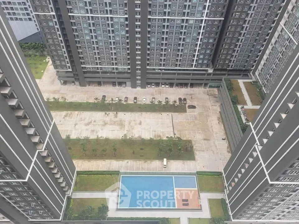 Stunning aerial view of modern high-rise apartment complex with pool and landscaped courtyard.