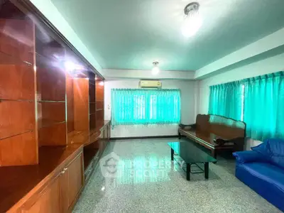 Spacious living room with vibrant green curtains and elegant wooden furniture, perfect for relaxation.