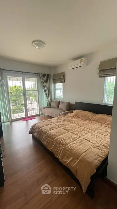 Spacious bedroom with large windows and cozy seating area