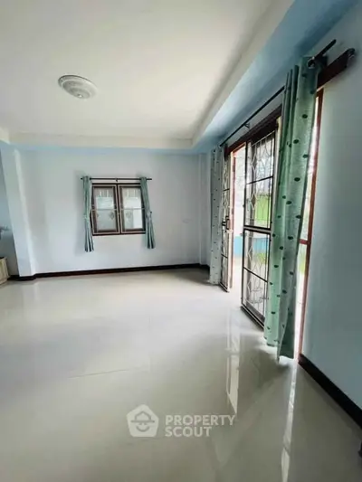 Spacious living room with large windows and polished floors, perfect for natural light lovers.