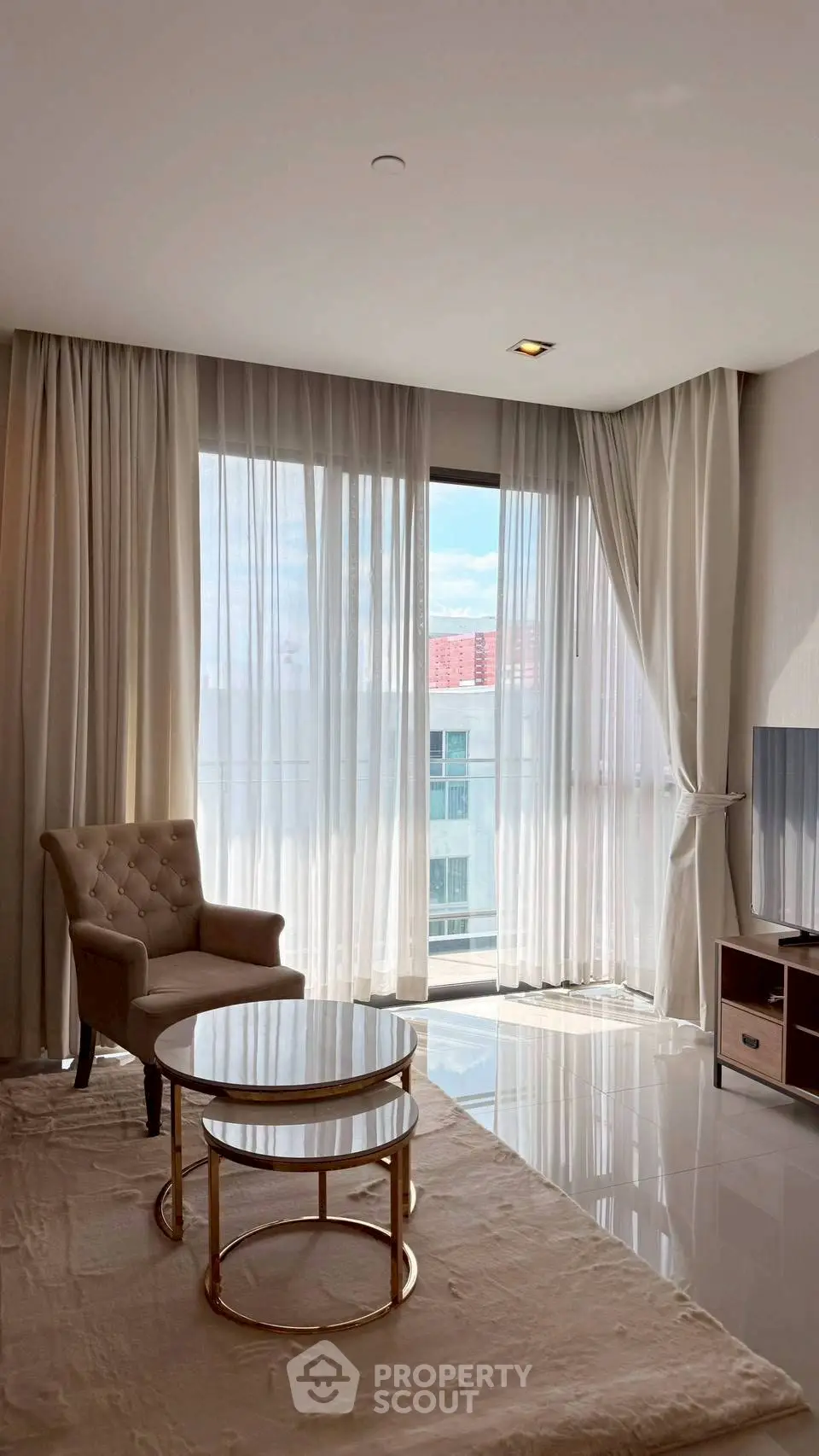 Elegant living room with modern furniture and large windows offering natural light and city views.