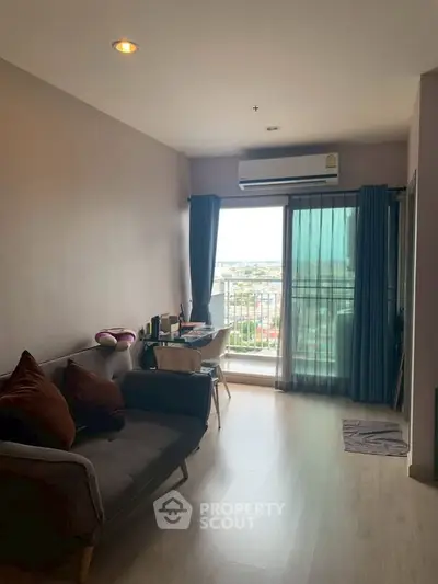 Modern living room with balcony view, featuring cozy sofa and natural light.