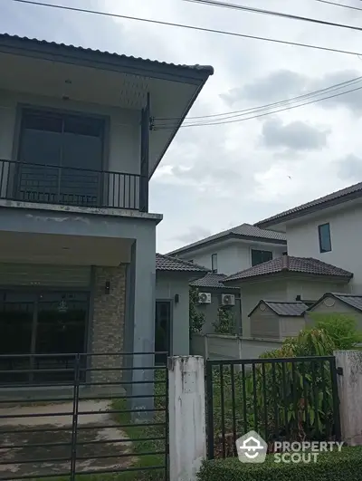 Modern two-story house with balcony and garden in suburban neighborhood