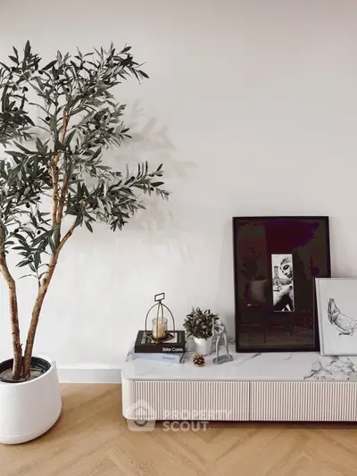 Stylish modern living room corner with potted plant and decor on wooden floor.
